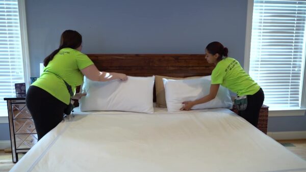 two EZ Pizzi Cleaning team members are making a king bed