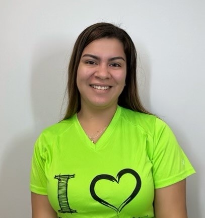 A woman wearing a green shirt with a heart on it.