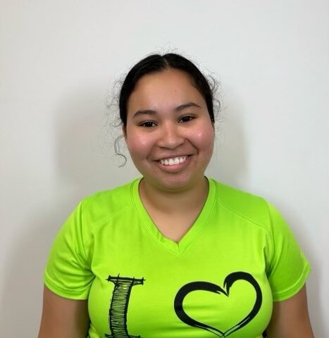 A young woman in a green shirt with a heart on it.