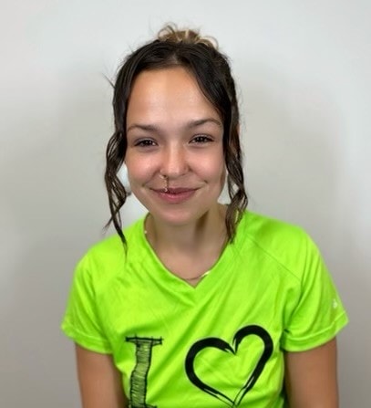 A young woman wearing a green shirt with a heart on it.