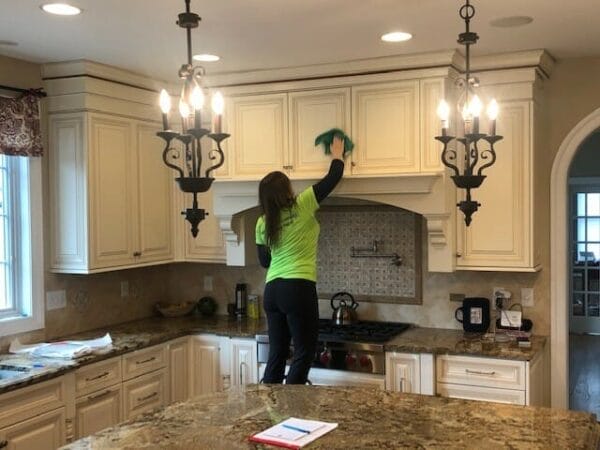 A woman cleaning a kitchen with a green mop.