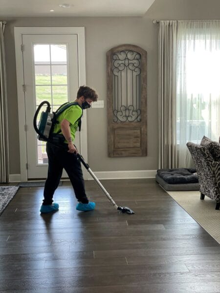 A man cleaning a hardwood floor in a living room.