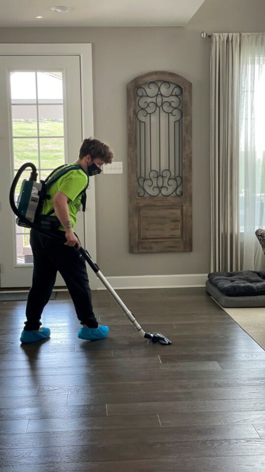 A man cleaning a hardwood floor in a living room.
