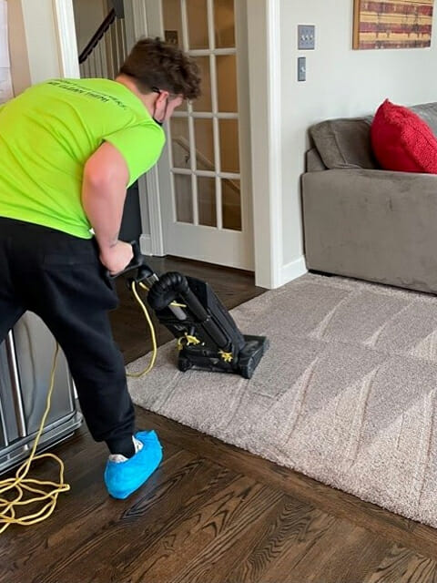 A man cleaning a carpet in a living room.