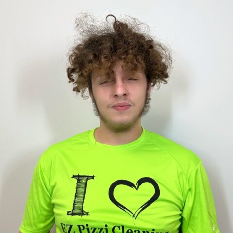 A young man wearing a green shirt with the words i love EZ Pizzi cleaning.