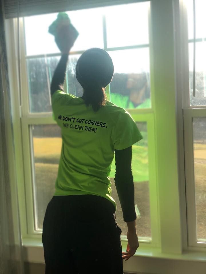 A woman in a green shirt cleaning a window.